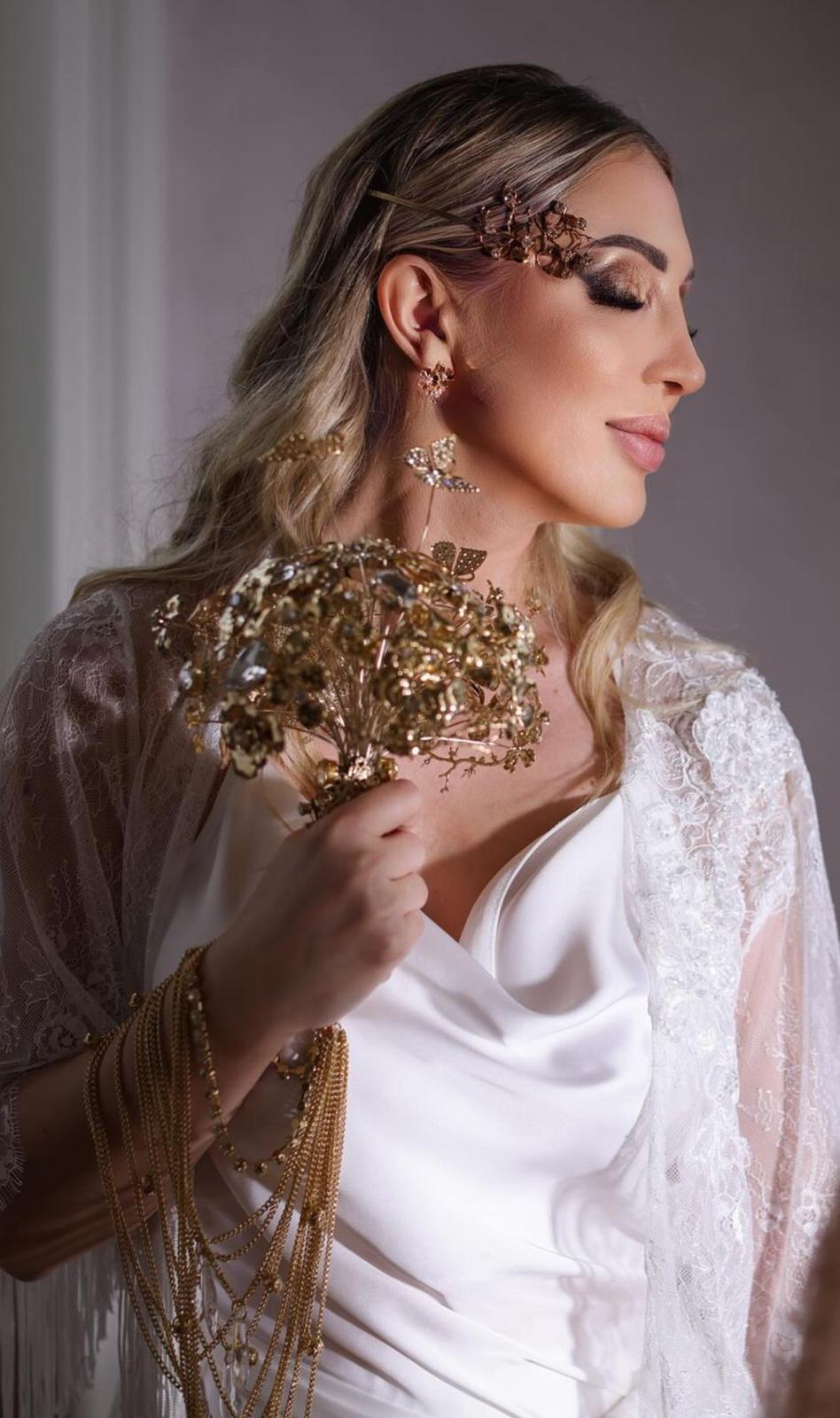 Sposa di profilo con occhi sfumati nei toni del bronzo, accessori e bouquet dorati