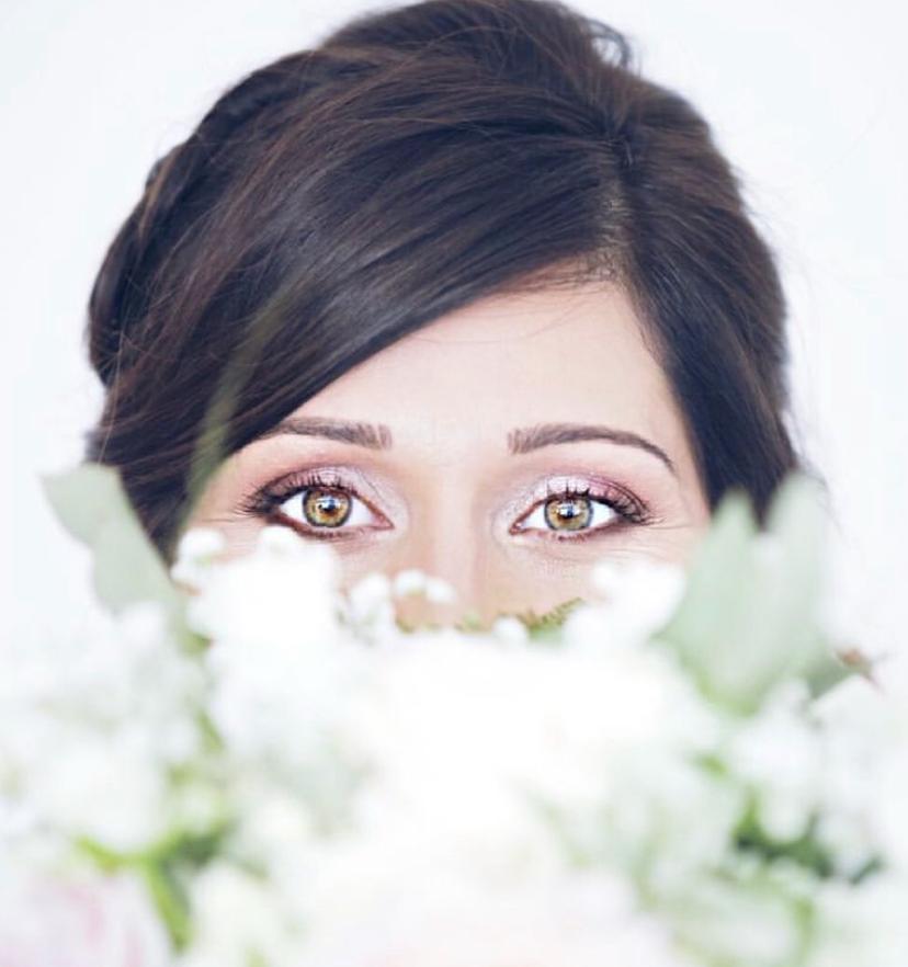 Occhi di una sposa che emergono da un bouquet di fiori bianchi
