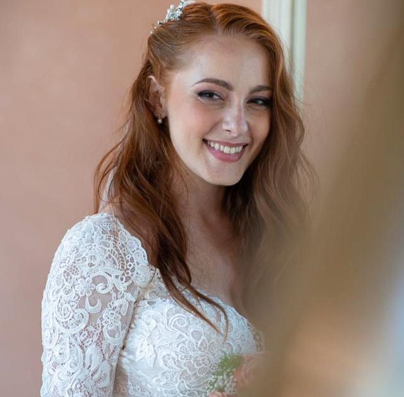 Sposa dai capelli rossi con diadema e abito di pizzo, sorridente