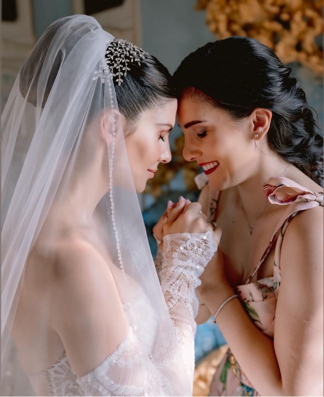 Sposa con velo e diadema, fronte contro fronte con un’amica